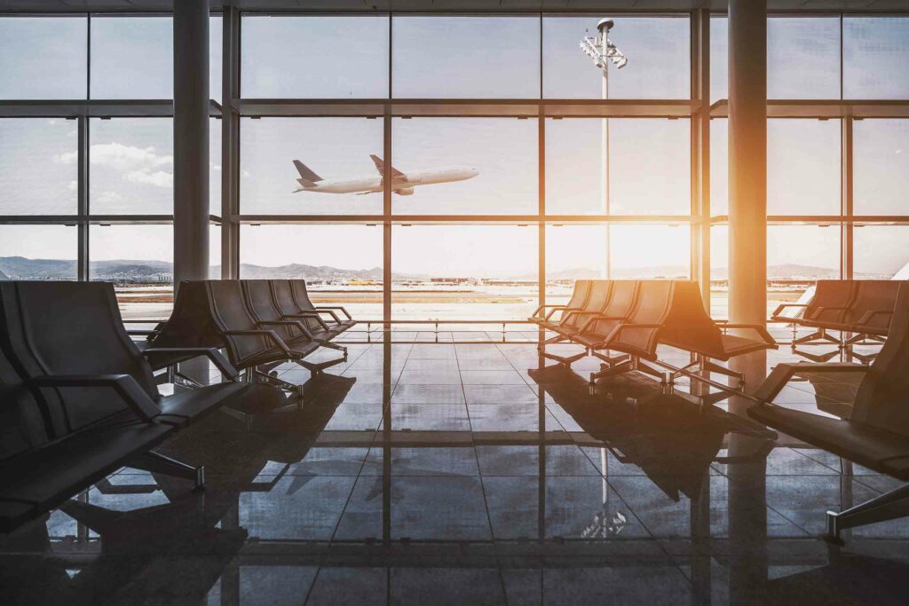 Empty airport waiting area with view of plane taking off from runway